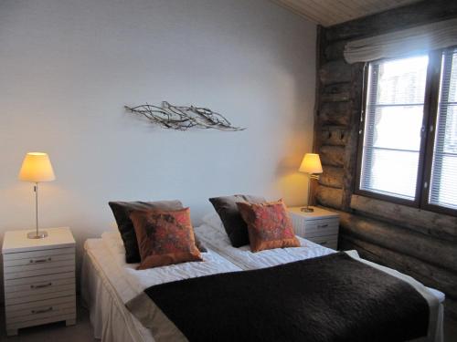 萨利色尔卡Lapin Kutsu Log Cabins的一间卧室配有一张带2个床头柜和2盏灯的床。
