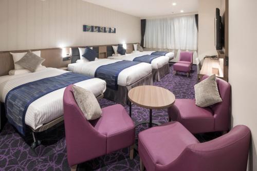 东京MYSTAYS 五反田站前酒店的酒店客房设有四张床和紫色椅子