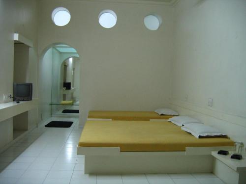 JālgaonHotel Plaza (BOOKING FOR FOREIGN TOURIST ONLY)的带三扇窗户的客房内的两张床