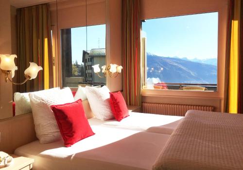 克莱恩 蒙塔纳福赫酒店的一间卧室配有一张带红色枕头的床和一扇窗户
