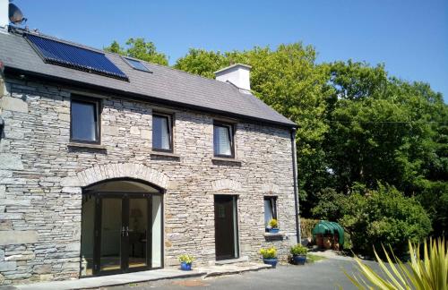 恩尼斯泰蒙SunnySide-Cottage的屋顶上设有太阳能电池板的石头房子