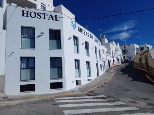 科尼尔-德拉弗龙特拉Hostal Brisas de Conil的一座白色的建筑,旁边有一个医院标志