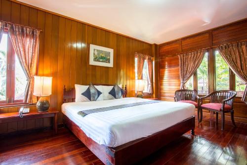查汶诺瓦苏梅岛度假酒店的一间卧室设有一张大床、木墙和窗户。