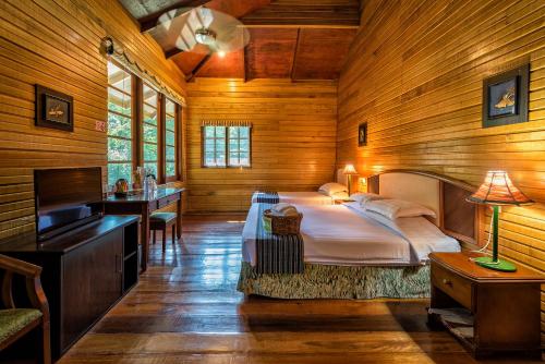 甘榜布提尔婆罗洲热带雨林度假村的木制客房内的一间卧室配有一张大床