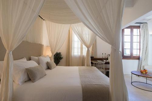 休达德亚S'Hotelet d'es Born - Suites & SPA的卧室配有带窗帘的大型白色床