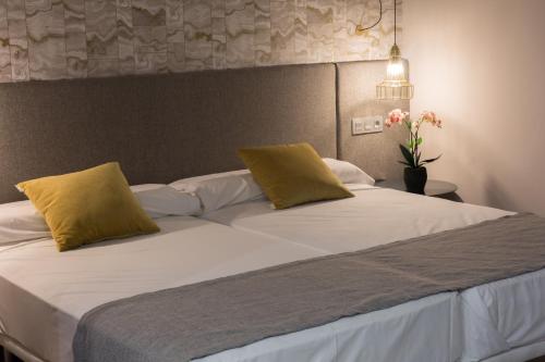 马贝拉Ona Marbella Inn的一张大床,上面有两个黄色枕头