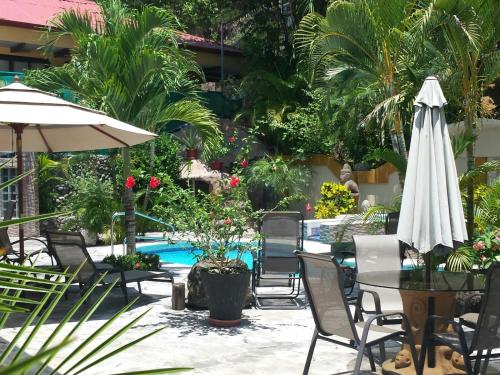 曼努埃尔安东尼奥Coyaba Tropical Elegant Adult Guesthouse的一个带桌子和遮阳伞的庭院和一个游泳池