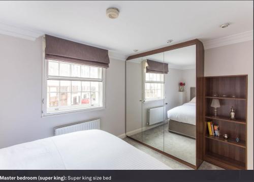 伦敦Heart of Mayfair - Stunning Apartment的一间带镜子和床的卧室