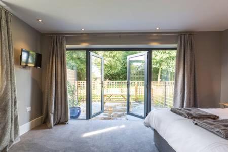 欧弗顿Oak & Hazel, Heath Row Barn的一间卧室设有一张床和一个滑动玻璃门