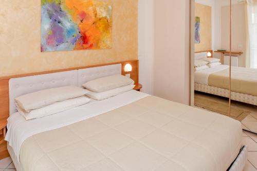巴多利诺Blue Lake Residence - Bardolino的卧室配有白色的床和镜子