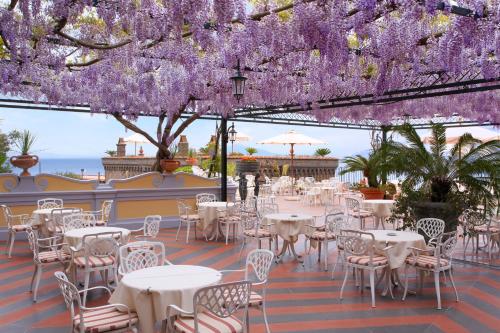 索伦托卡波迪蒙特大酒店的紫色花冠下方的带桌椅的天井