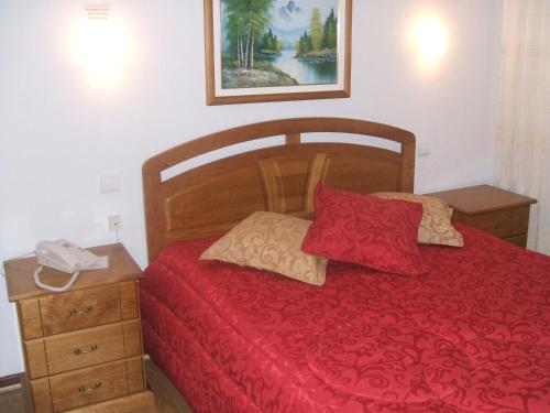 瓜尔达平托旅馆的一间卧室配有一张红色的床,上面有电话