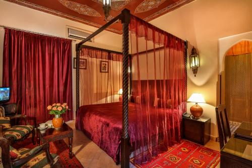 马拉喀什里亚德水疗巴伊亚萨拉姆酒店的一间卧室配有一张带红色窗帘的天蓬床