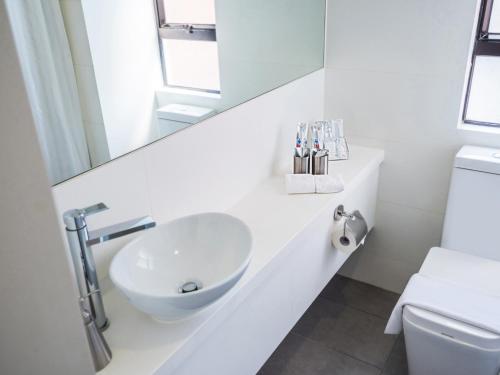 香港九龙彩鸿酒店的白色的浴室设有水槽和镜子