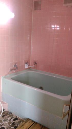 Maisaka高梁卡施布奈藤传统日式民宿的浴室设有浴缸,铺有粉红色的瓷砖。