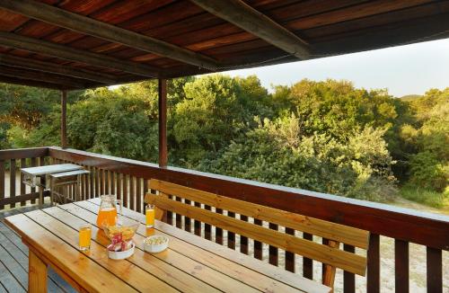 索德瓦纳湾First Group Sodwana Bay Lodge Self Catering的甲板上的木凳和桌子