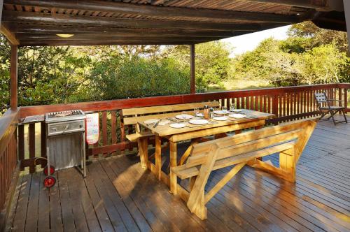 索德瓦纳湾First Group Sodwana Bay Lodge Self Catering的木甲板配有桌子和炉灶