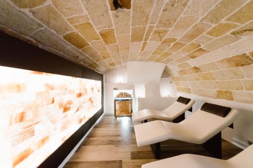 滨海波利尼亚诺吉奥维雷拉斯酒店的一间设有白色椅子和石头天花板的房间