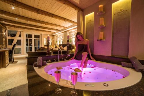 WingerodeSpa Villa Beauty & Wellness Resort的坐在按摩浴缸中的女士,带两杯酒杯