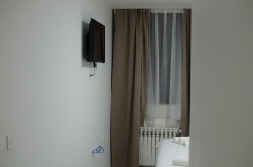 GackoHotel Metohija的一间卧室配有一张床、电视和窗帘