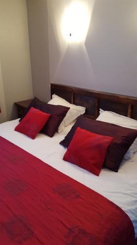勒梅尼勒莱斯萨潘斯酒店的一间卧室配有两张带红色和黑色枕头的床