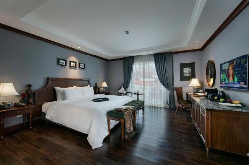 河内La Sinfonía Majesty Hotel and Spa的卧室配有一张白色大床和一张书桌