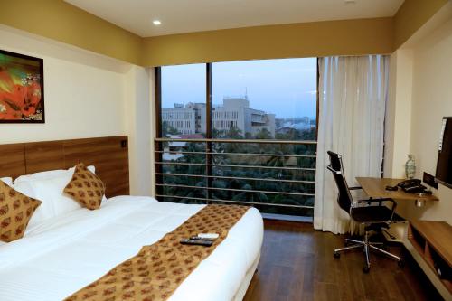 孟买Hotel Mumbai House Andheri East, Mumbai的配有一张床、一张书桌和一扇窗户的酒店客房
