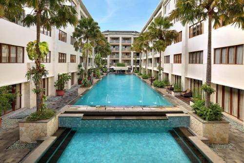 库塔Aston Kuta Hotel and Residence的棕榈树建筑中间的游泳池