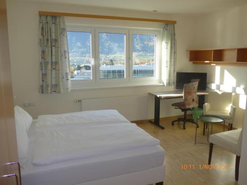 斯皮特安德劳Kolpinghaus Spittal的酒店客房设有一张床、一张书桌和窗户。