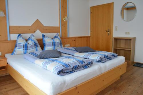 莱奥冈Gästehaus Huber的一张配有蓝色和白色毯子及枕头的大床