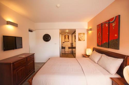 班拉克海滩Replay Condo One Bedroom的卧室配有白色的床和平面电视。