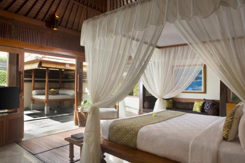 乌布乌布乡村酒店的一间卧室配有一张带窗帘的床和电视。