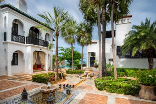 盼武里摩洛哥别墅度假村的享有棕榈树和喷泉房屋的外部景色