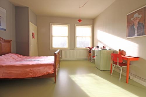 阿姆斯特丹Cafe Modern的一间卧室配有一张床铺和一张桌子,还设有一间厨房