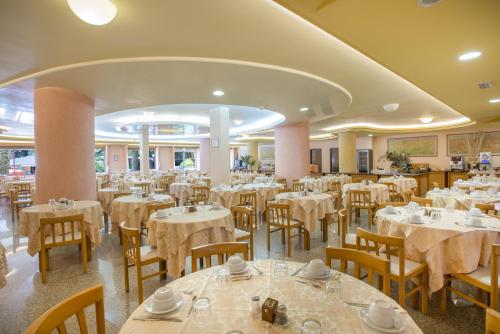 阿尔盖罗绿洲酒店的用餐室配有桌椅和白色床单