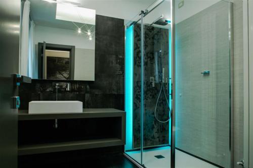 罗马威尼托大街豪华套房酒店的一间带水槽和玻璃淋浴的浴室