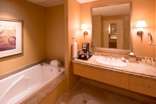 什里夫波特Bally's Shreveport Casino & Hotel的带浴缸、水槽和镜子的浴室