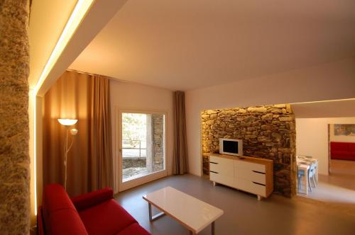 吉法Rustico Moderno的客厅设有红色的沙发和石墙