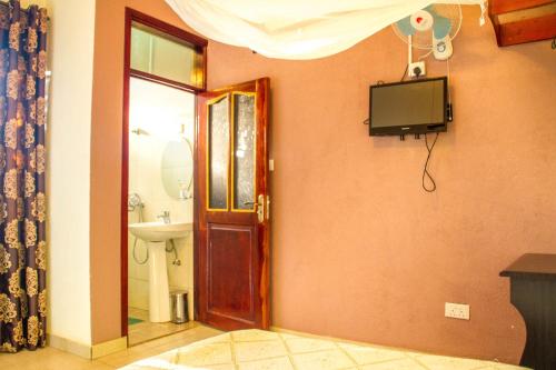 KitendeHotel Gorilla's Nest Entebbe的一间带卫生间的浴室和墙上的电视