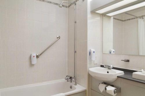 汤顿戴斯陶顿酒店的一间带水槽、浴缸和镜子的浴室