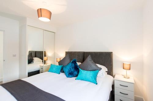 赫默尔亨普斯特德Abodebed Oval View Apartments的一间卧室配有白色床和蓝色枕头