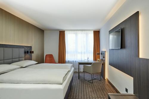 拜罗伊特拜罗伊特王宫H4酒店的配有一张床和一张书桌的酒店客房
