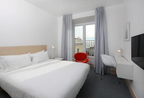 里斯本萨尔瓦多修道院酒店的酒店客房设有一张大床和一张红色椅子。