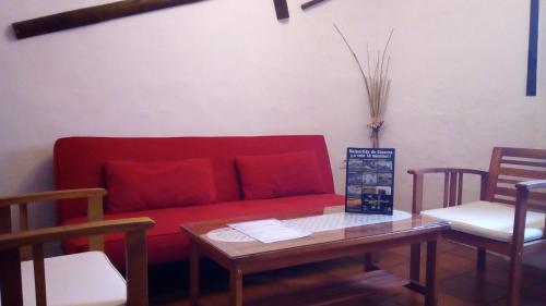 马尔帕尔蒂达德卡塞雷斯卡萨乡间玛丽亚旅馆的客厅配有红色的沙发和两把椅子