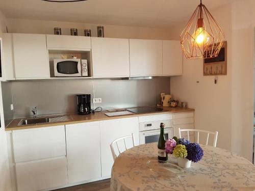 佩罗斯-吉雷克Côte de Granit Rose的厨房配有白色橱柜和鲜花桌