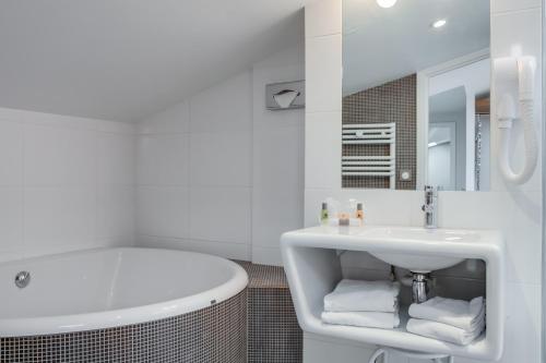 枫丹白露The Originals Boutique, Hôtel Victoria, Fontainebleau的白色的浴室设有浴缸和水槽。