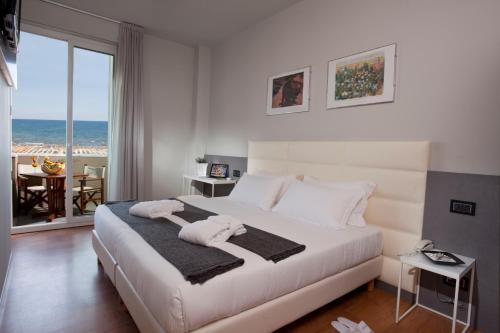 里米尼Hotel Ascot & Spa的卧室设有白色床,享有海景