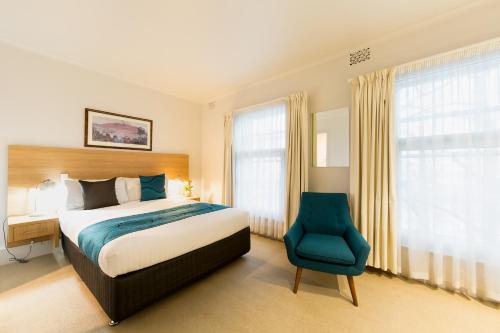 霍巴特海关大厦酒店的一间卧室配有一张床和一张蓝色椅子