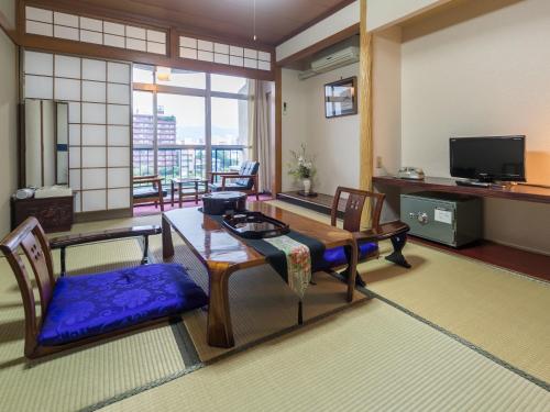 高知昭荣河滨日式旅馆的客厅配有桌椅和电视。