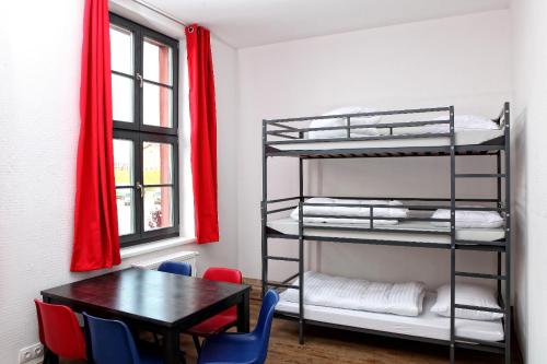 新勃兰登堡Hostel am GÜTERBAHNHOF的客房设有一张桌子和一张双层床。